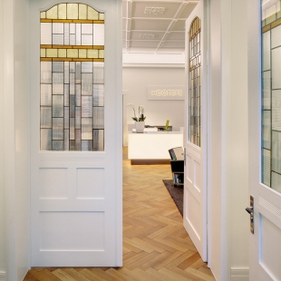 Die restaurierten, mit Buntglas versehenen Türen verschönern den Eingang zum Verlag.