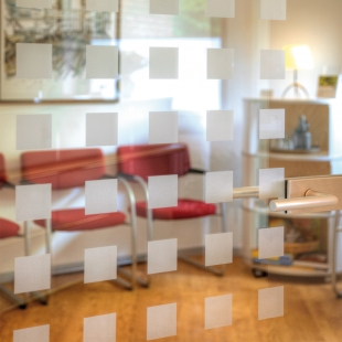 Auch der Wartebereich überzeugt durch eine harmonische Farbgestaltung. Der gut beleuchtete Raum ist durch eine Glastür mit der Praxis verbunden, die Wartenden fühlen sich nicht abgeschottet.